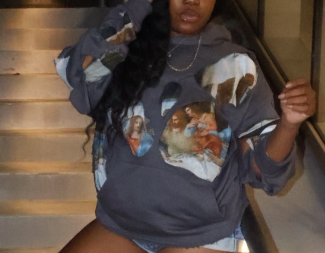 Woman wearing a graphic sweatshirt and knee-high boots on a staircase at night.